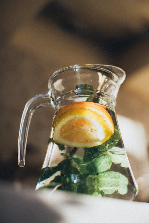 Water with sliced lemon in pitcher, infused with lemon balm herbal tea for better sleep