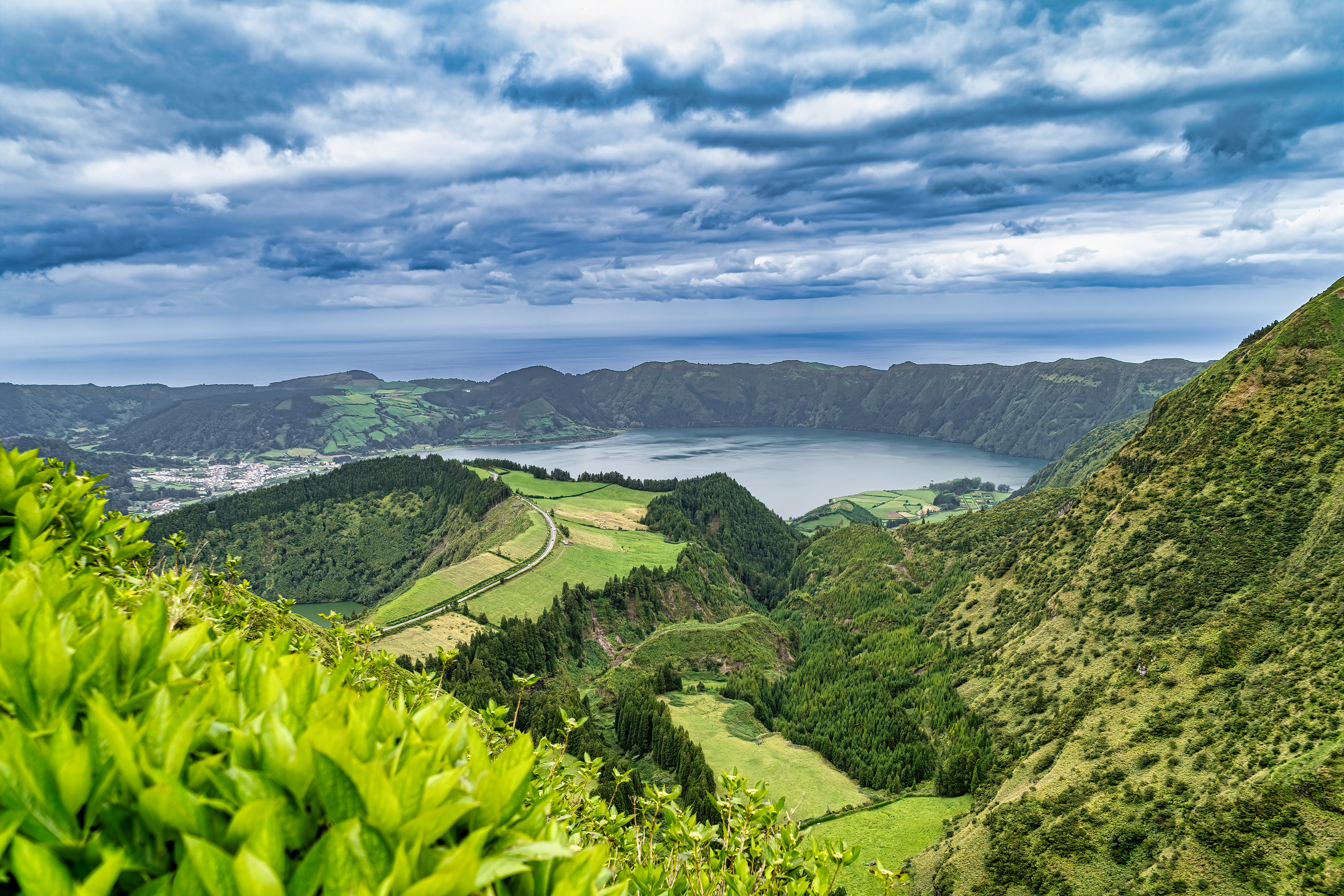 Twin blue and green crater lakes nestled in volcanic caldera at Sete Cidades, São Miguel Island, Azores during misty morning light