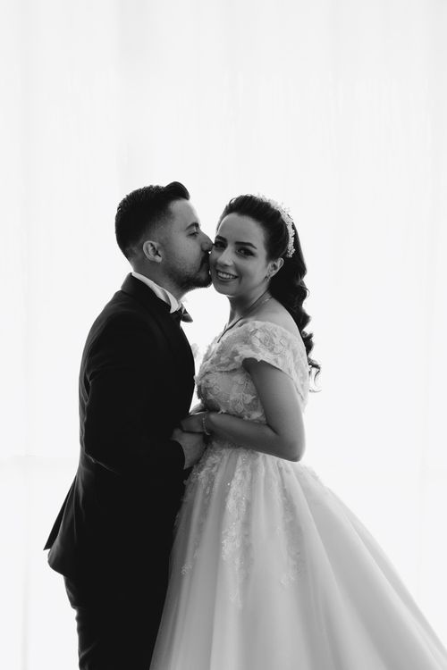 Free Black and white photo of a bride and groom sharing an affectionate moment. Stock Photo