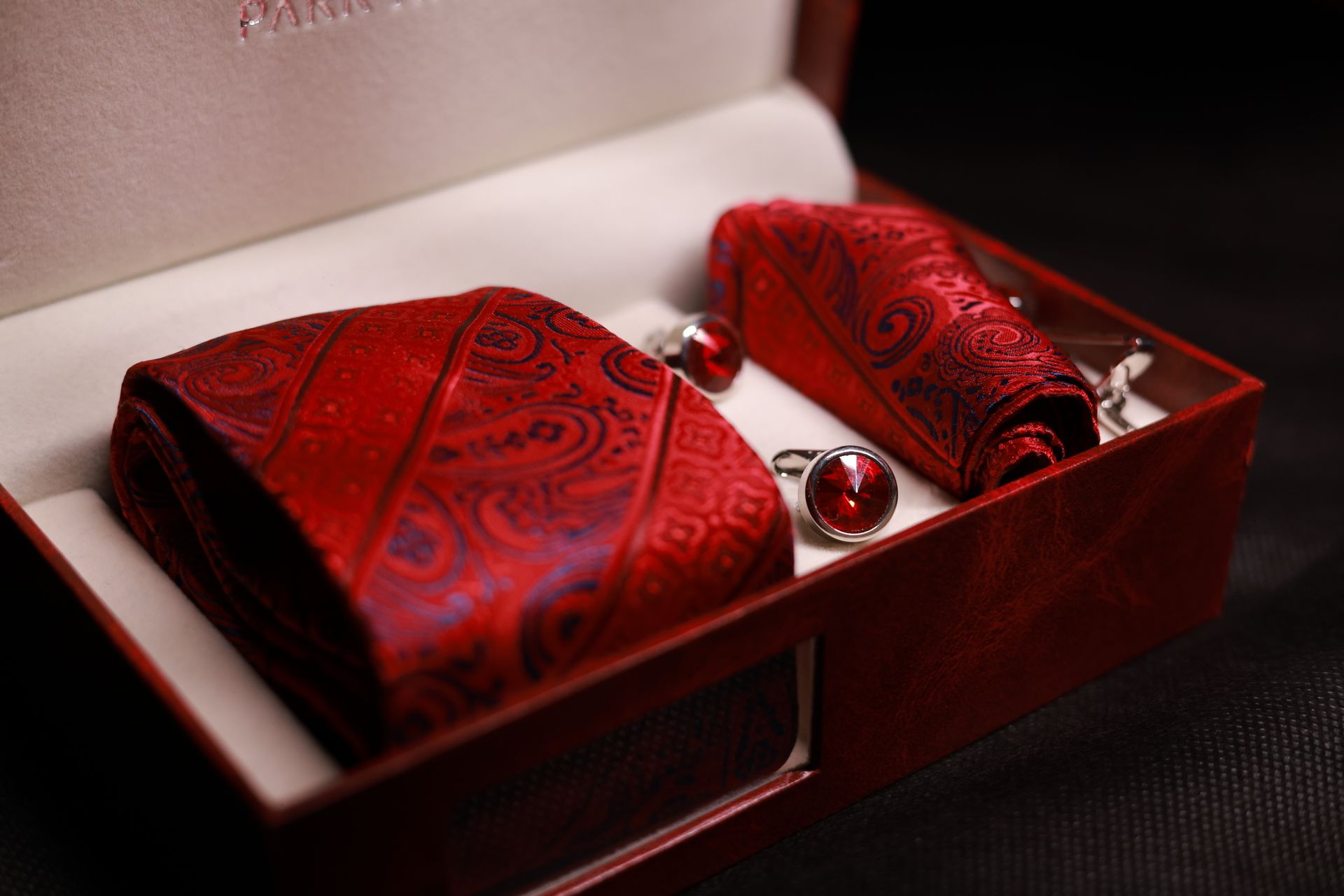 A Box With a Folded Red Silk Neck Tie, Handkerchief and Cuff Links