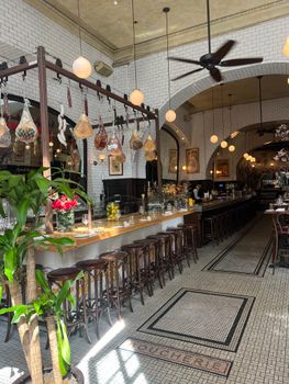 Chic interior of a luxury bar with stools and decorative hanging lights, ideal for a cozy night out.