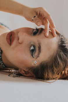 Portrait of a woman with creative makeup lying down, showcasing elegance and fashion in São Paulo.