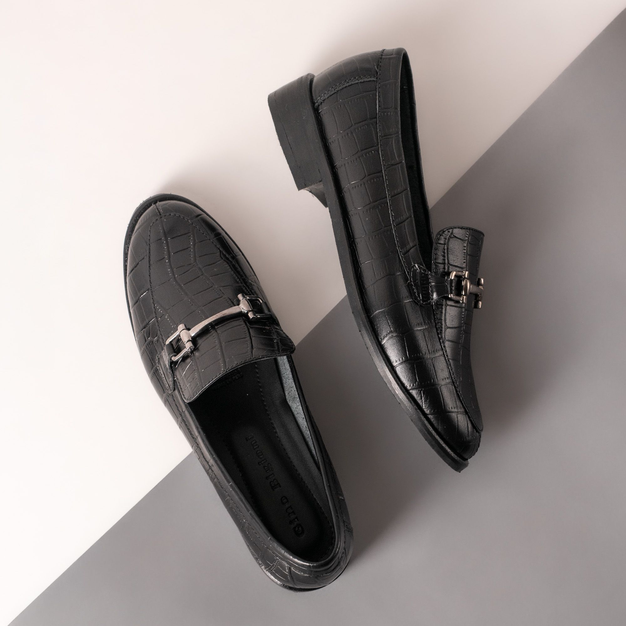 Black textured leather loafers on a grey and white backdrop — photo by José Martin Segura Benites on Pexels