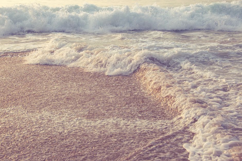 Peaceful ocean waves gently rolling onto a sandy beach at sunrise, capturing the serene coastal beauty.
