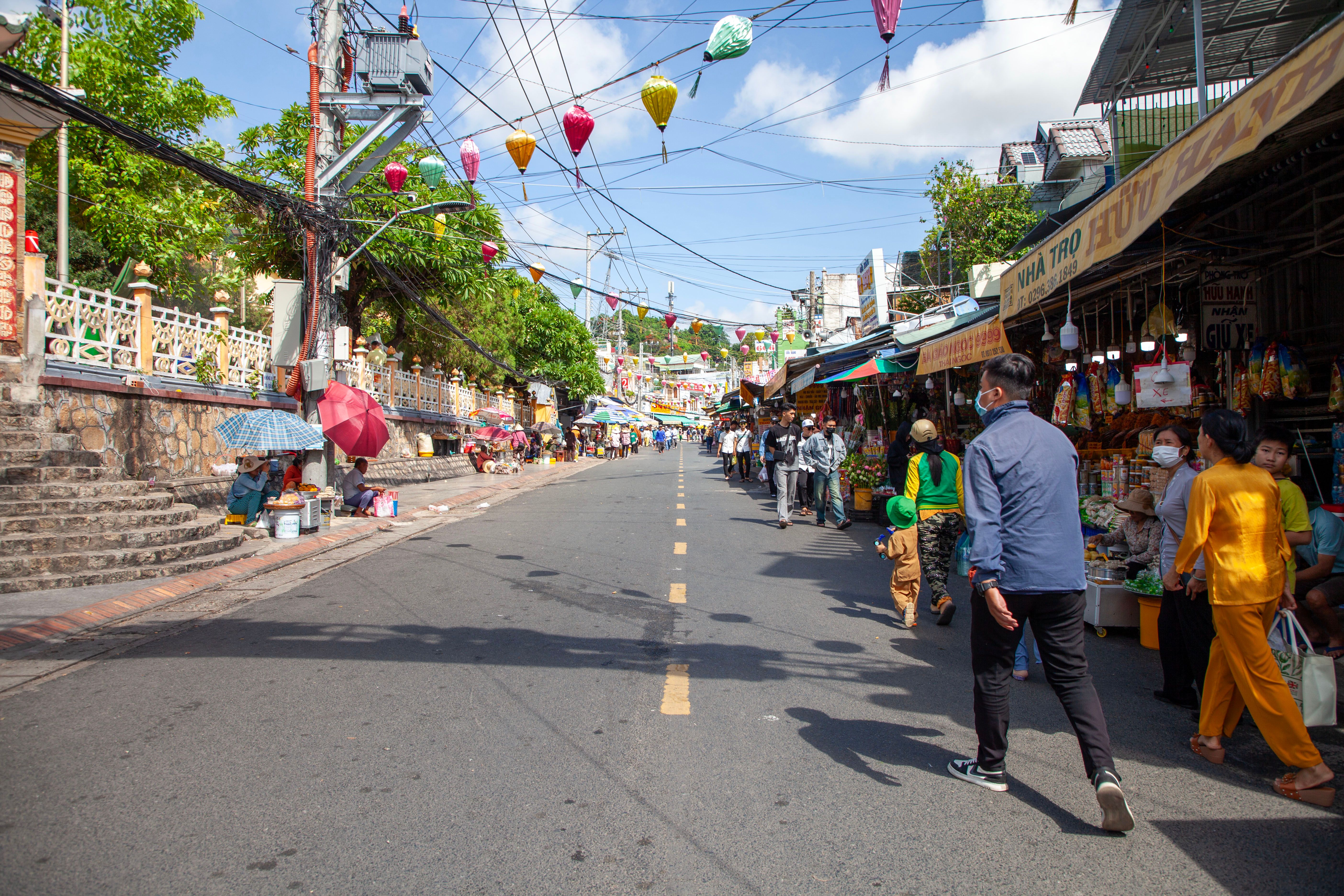 A crowded street market in a Southeast Asian city with tourists and locals mixing