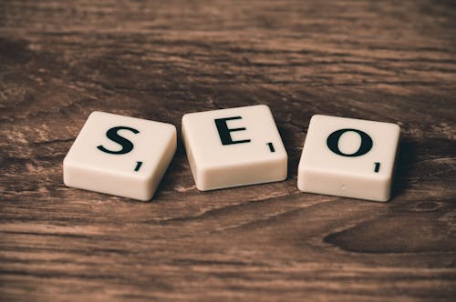 Free Scrabble tiles spelling 'SEO' on a wooden surface. Ideal for digital marketing themes. Stock Photo