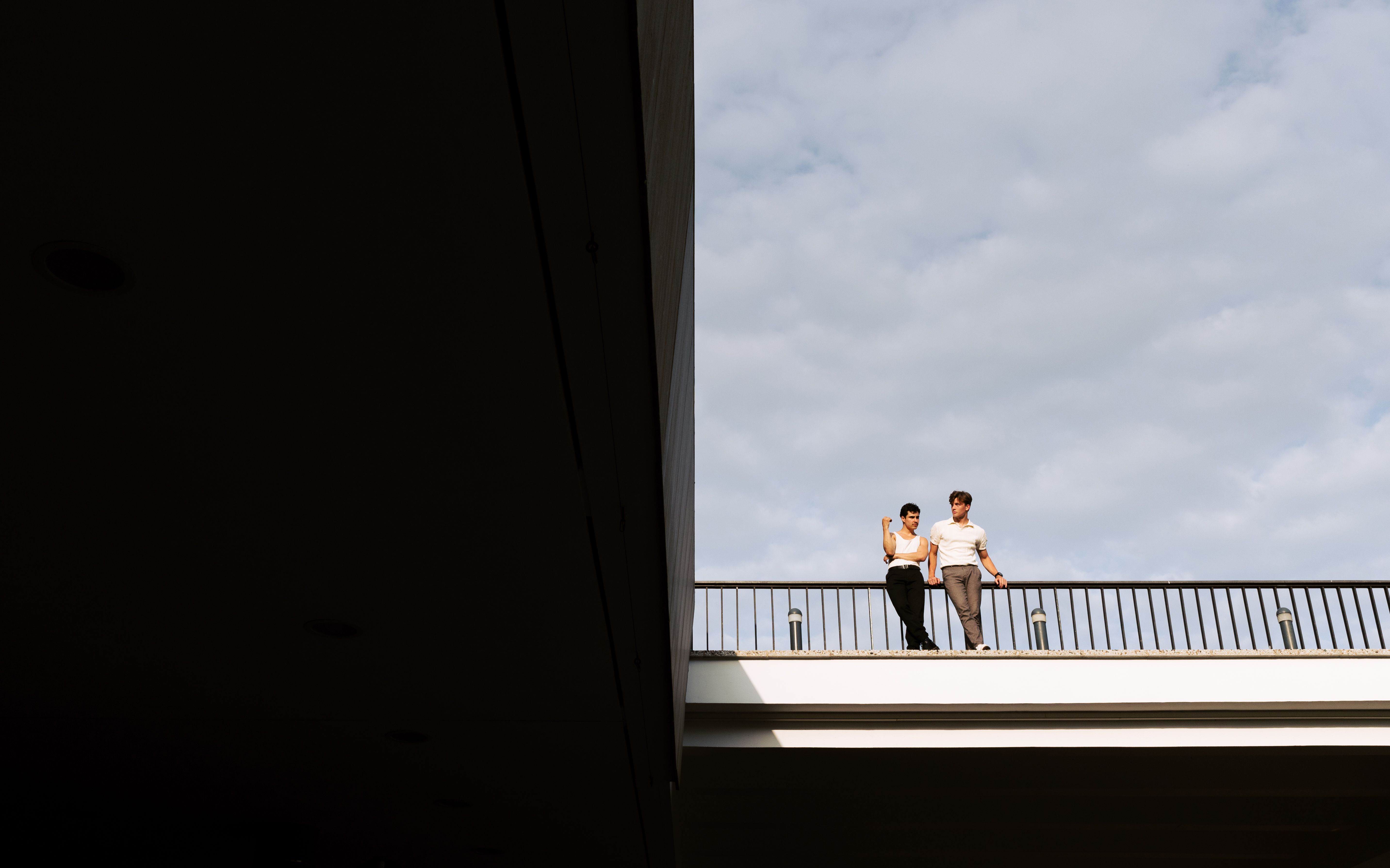 A couple stands on a bridge in Berlin, enjoying a cloudy day. Clear blue sky above.