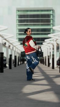 Trendy woman in streetwear posing outdoors in a stylish urban environment.
