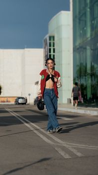Trendy woman in jeans and a jacket walking confidently in a city setting. Urban fashion highlighted.