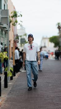 Man in casual attire walking down a vibrant city street