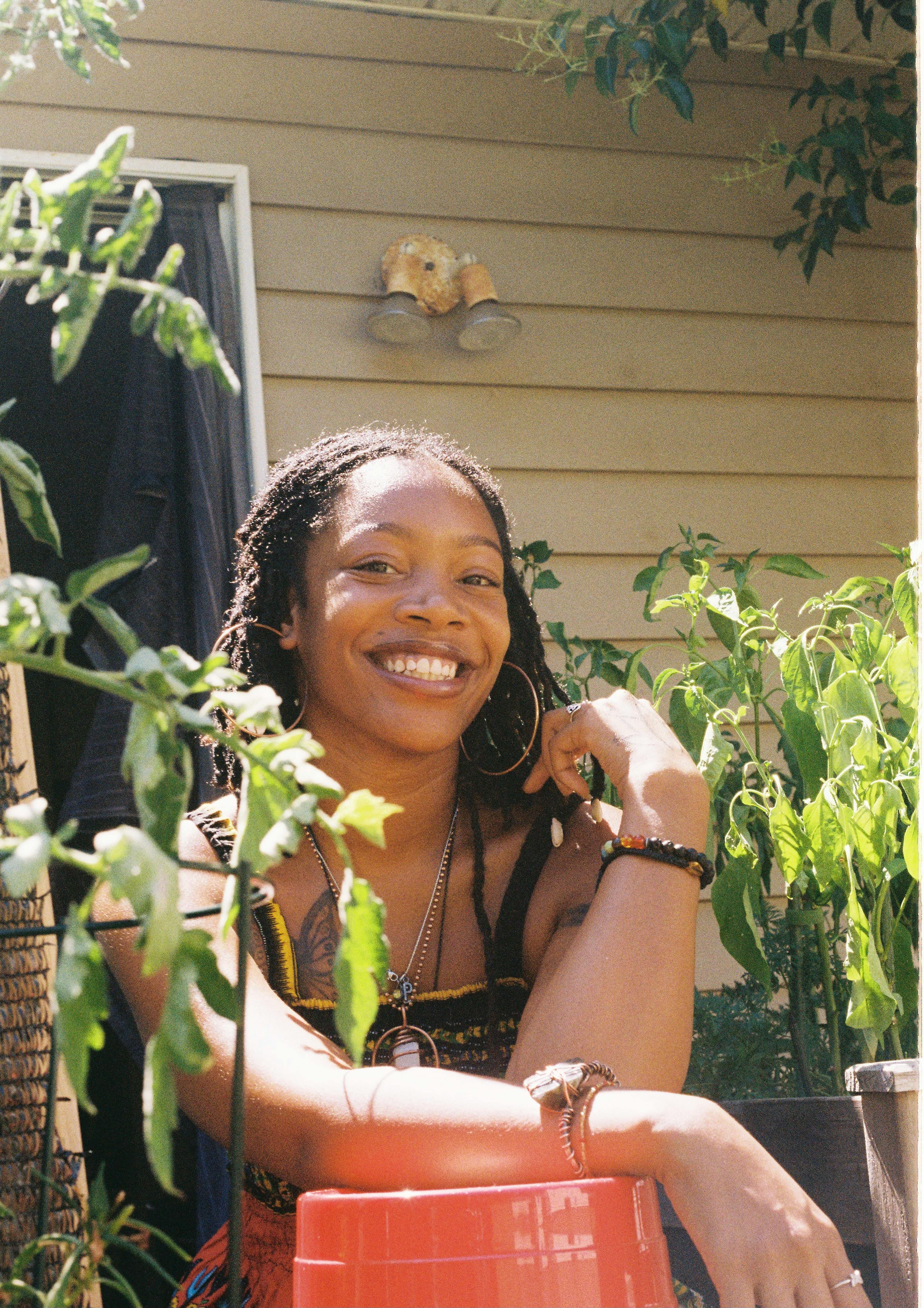 a smiling young woman sitting in a garden