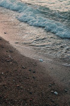 Peaceful waves and sandy beach create a calm coastal scene during sunset.