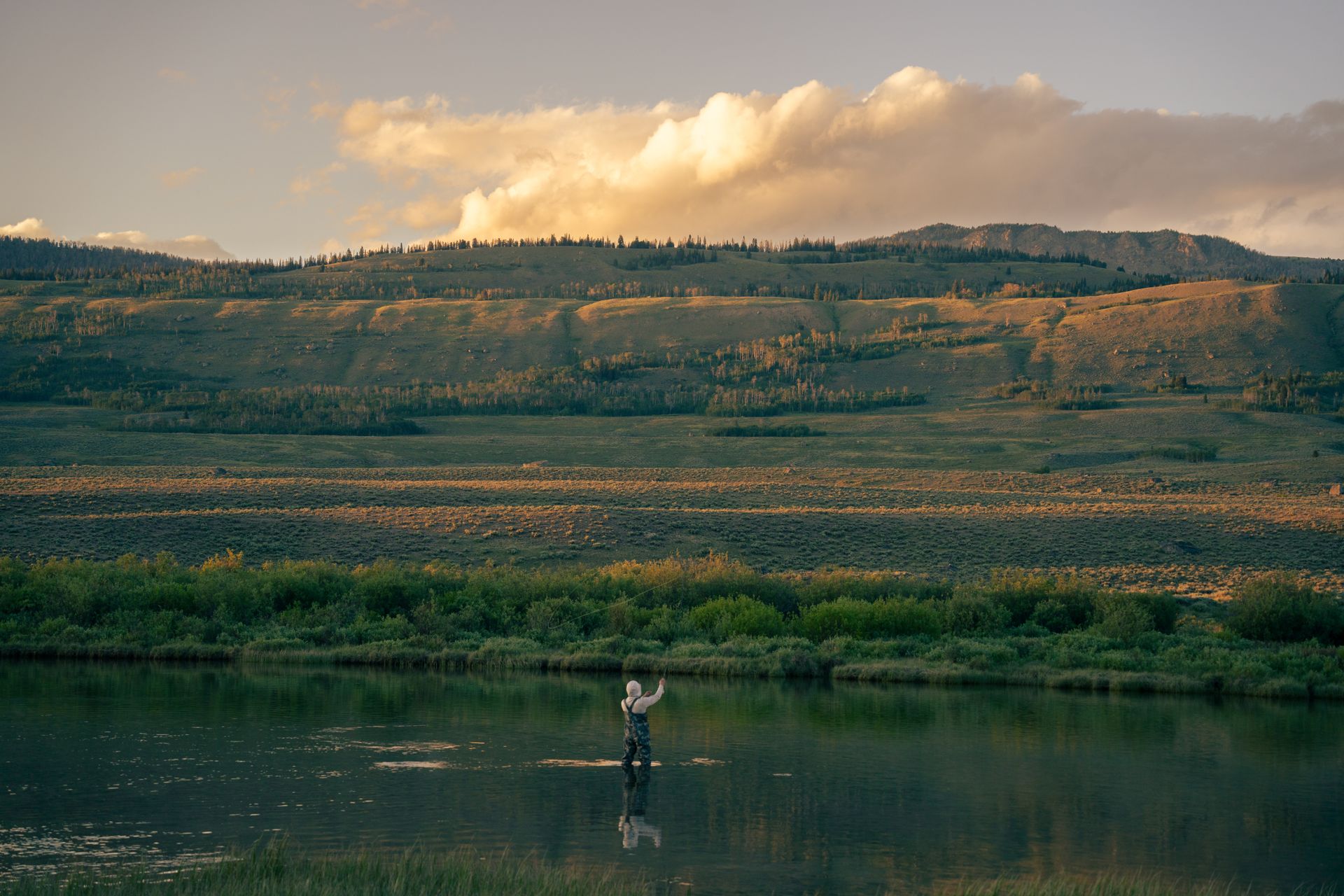 A serene scene of fly fishing at sunset in Pinedale, Wyoming.