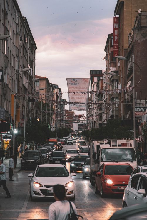 Free Traffic jams a busy city street at dusk, surrounded by tall buildings and vibrant urban life. Stock Photo