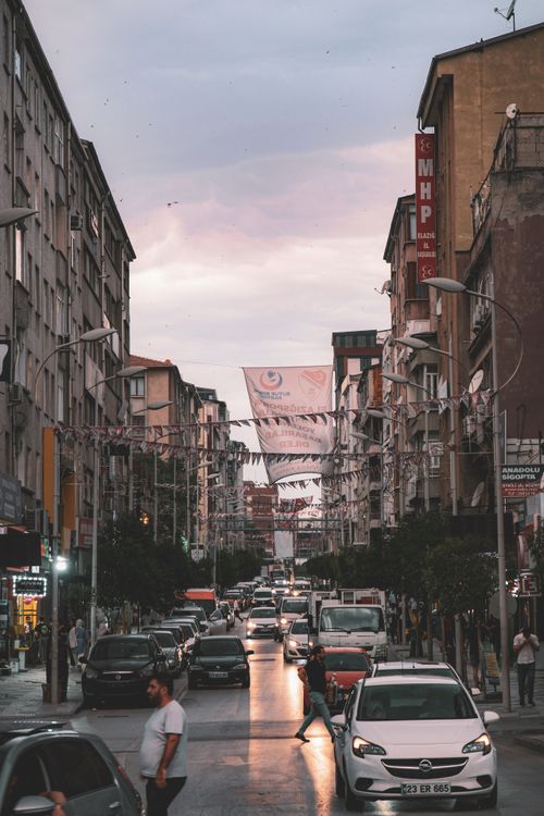Free Bustling city street filled with cars and pedestrians at sunset, capturing urban life. Stock Photo
