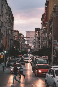 Busy city street scene with pedestrians and traffic in an urban environment at sunset.