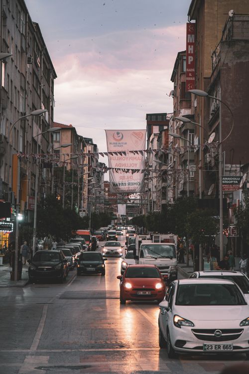 Free Evening traffic on a busy urban street with buildings and cars under a twilight sky. Stock Photo