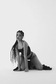 Black and white portrait of a woman in stylish lingerie posing on a white background.