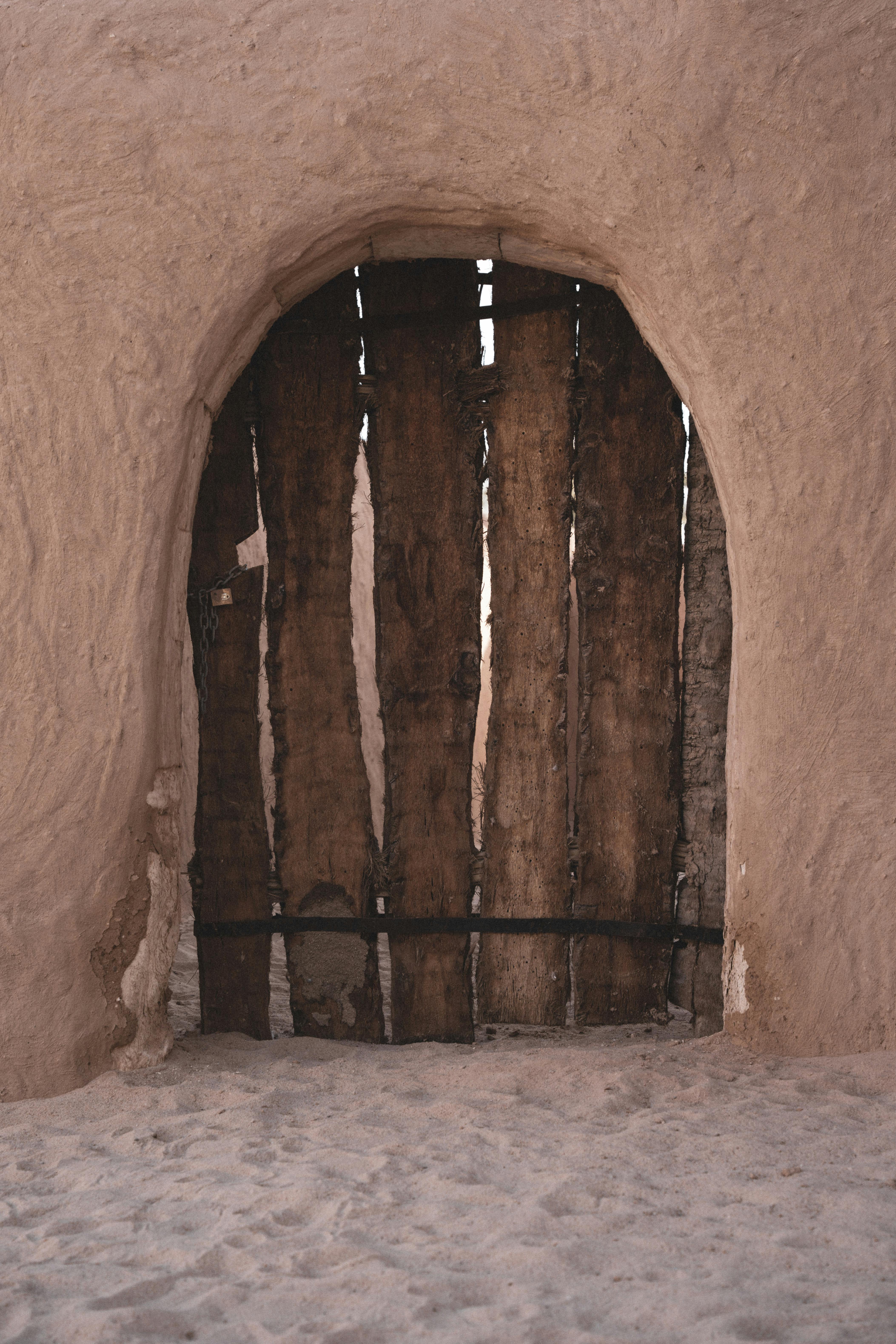 A rustic wooden door set in an adobe wall, capturing the essence of a Libyan desert village.
