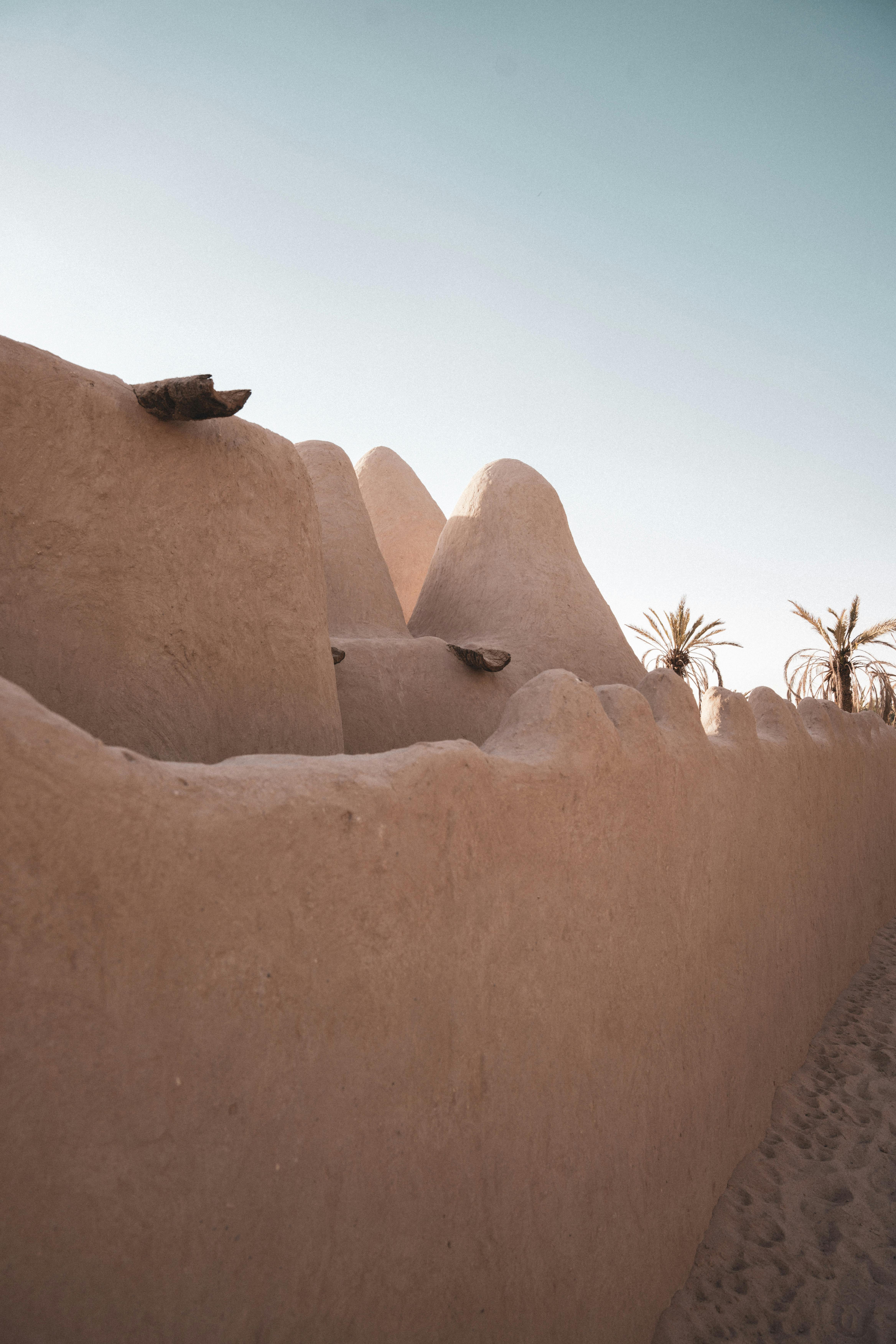 Безкоштовне Глиняні будівлі в стилі саману з пальмами під чистим блакитним небом, що відображають традиційну архітектуру. стокове фото