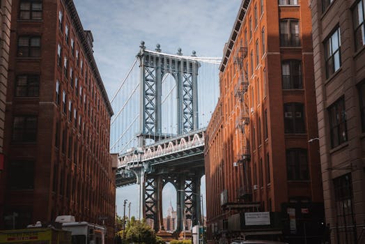 Stunning view of the Manhattan Bridge framed by red-brick buildings in New York City's DUMBO neighborhood. by Mario Cuadros