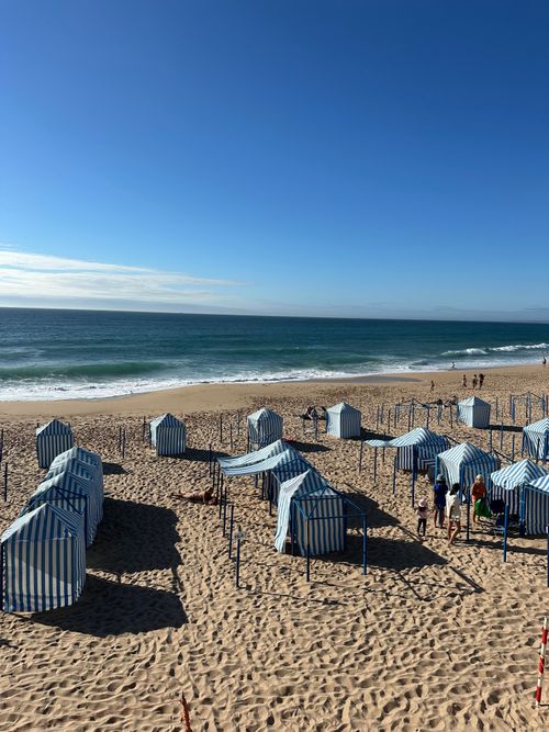 Free A sunny day at Silveira beach with striped tents and clear blue sky. Stock Photo