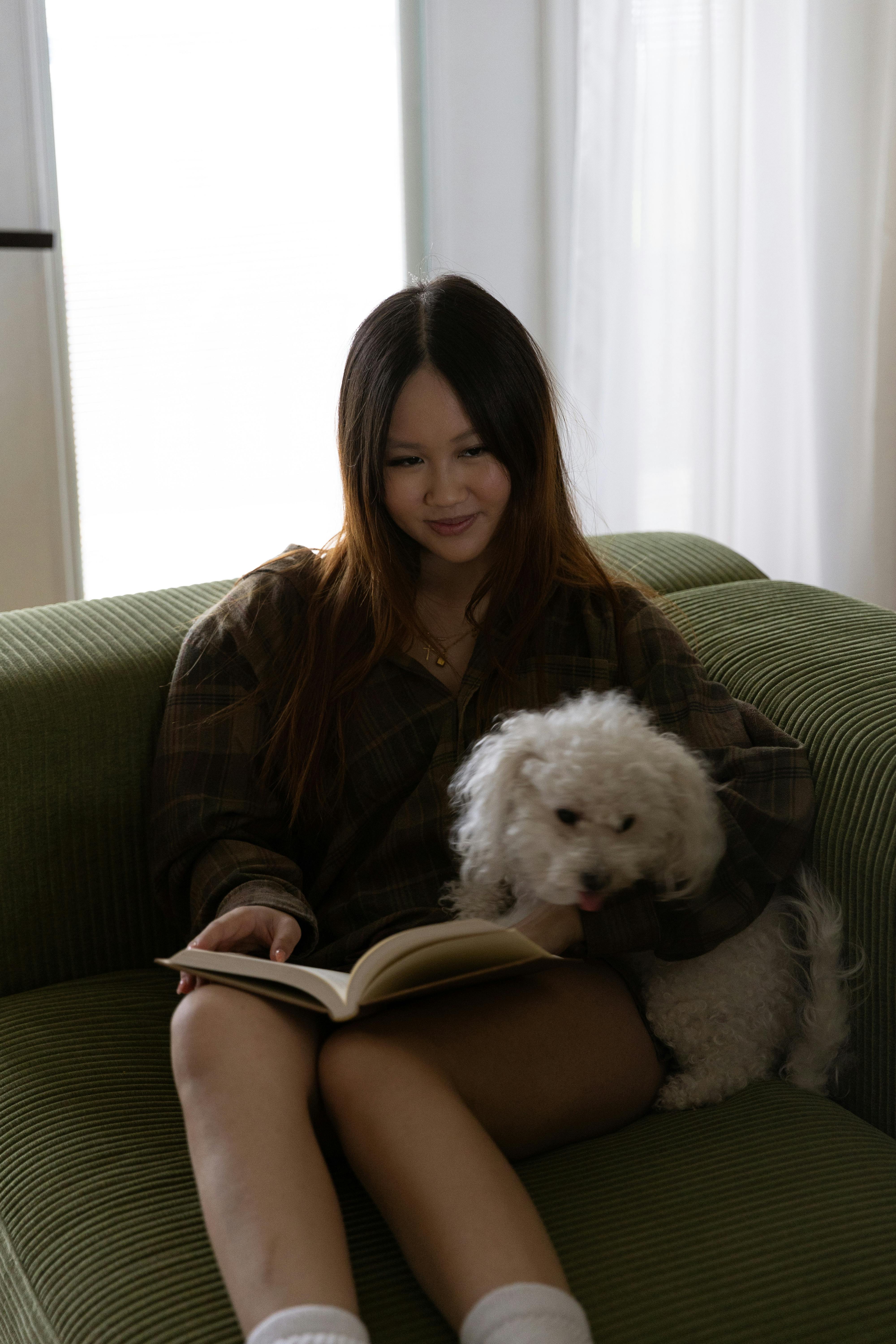 young brunette with dog and book on sofa