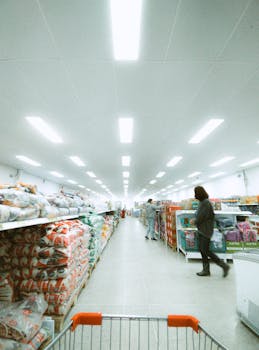 Wide supermarket aisle in Rionegro, Colombia with people shopping, captured from trolley perspective.