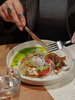 Delicious gourmet dish featuring poached egg, cucumber, and tomato with a side of greens, perfect for breakfast.