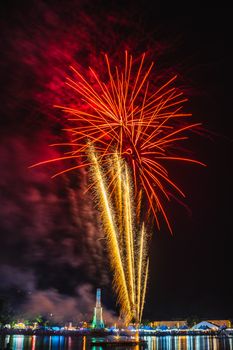 Vibrant fireworks lighting up the night sky above an urban landscape, reflecting on the water.