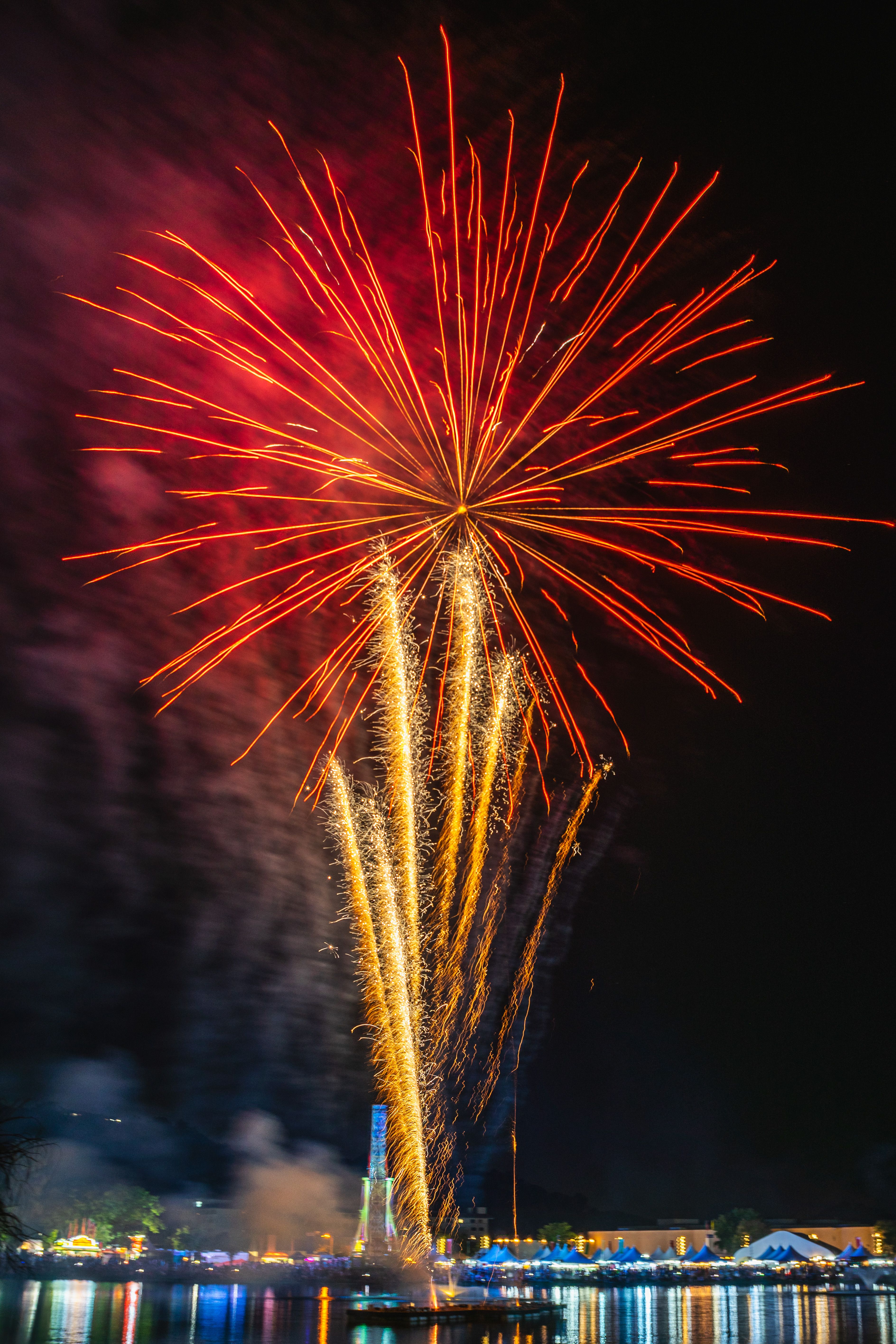 Spectacular fireworks lighting up the night sky over a lively waterfront festival.