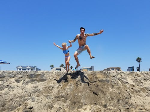 Foto De Um Homem E Uma Menina Pulando Na Areia