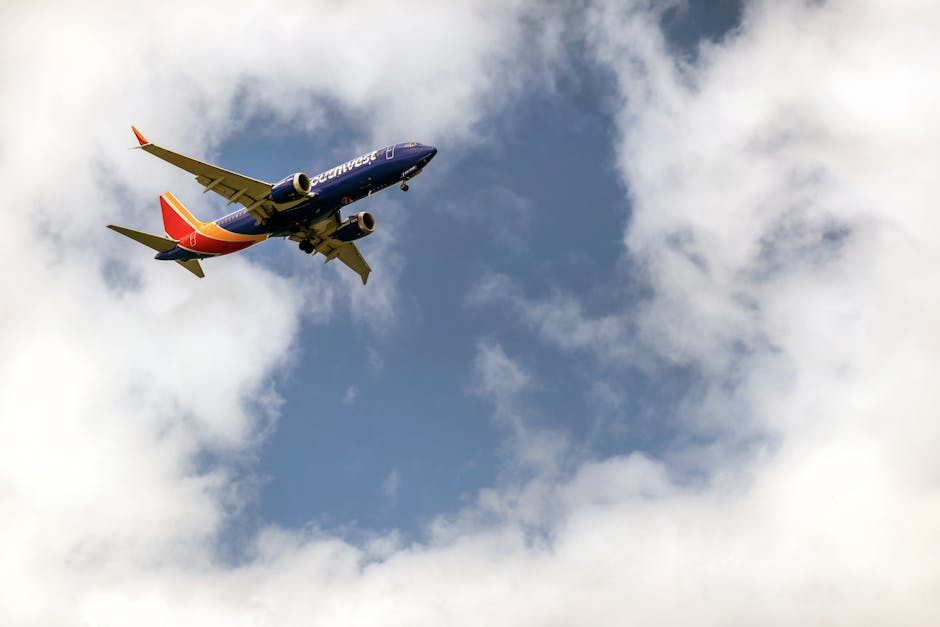 Photo by Tim Mossholder A vibrant airplane flying amidst scattered clouds in a clear blue sky, captured from below.