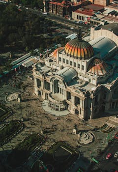 Stunning aerial shot of the iconic Palacio de Bellas Artes in Mexico City, showcasing its vibrant dome and historic architecture.