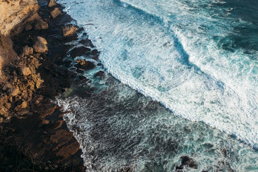 A stunning aerial view of Bali's rocky coast with waves crashing against the shore.