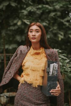 一位时尚女性在户外优雅地拿着盒子摆姿势，展现现代针织风格