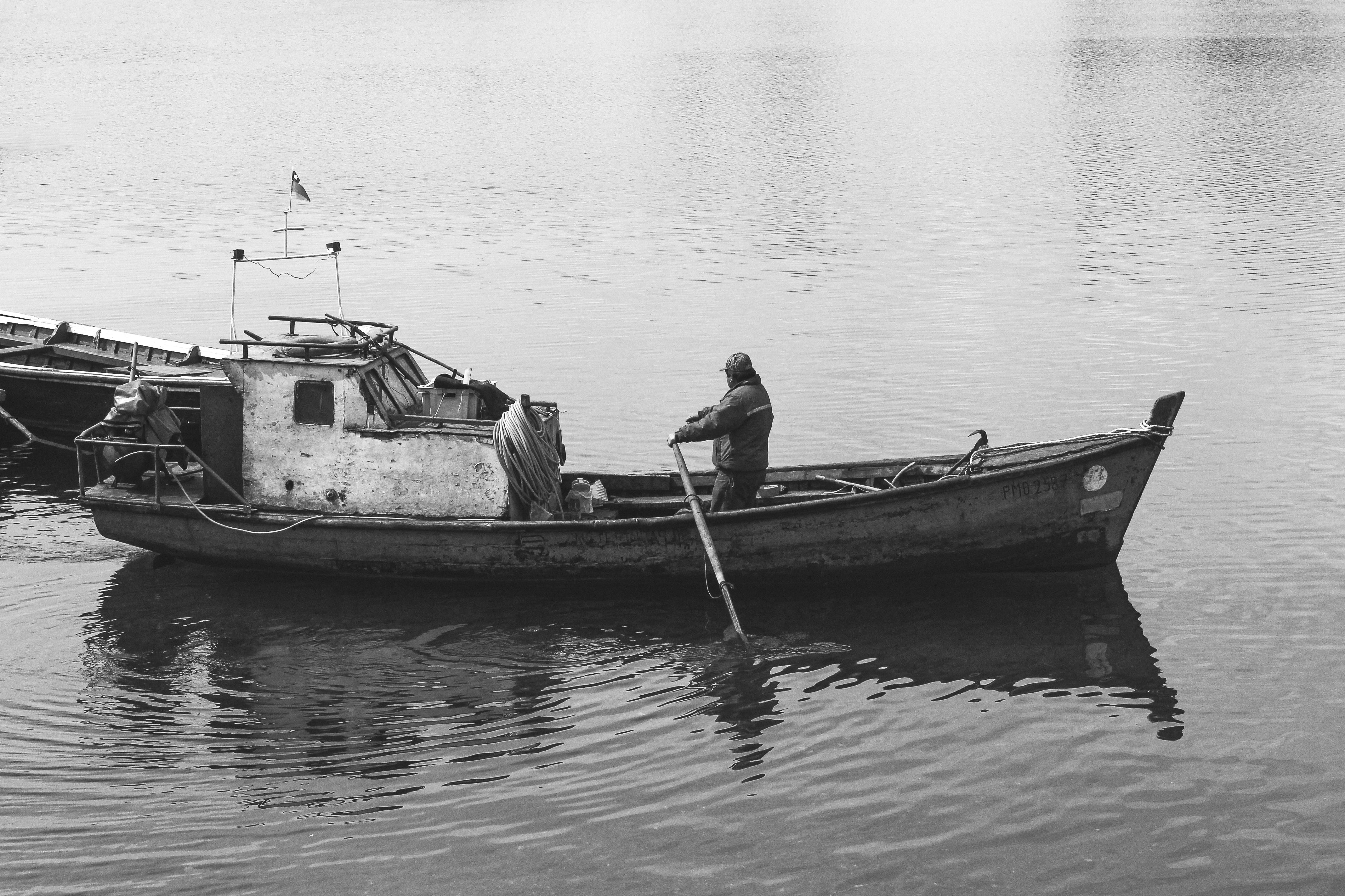 Black and white photo of a fisherman rowing his boat in Puerto Montt, Chile.