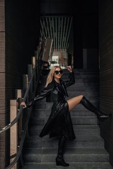 Stylish woman in sunglasses posing confidently on an urban staircase in fashion attire.