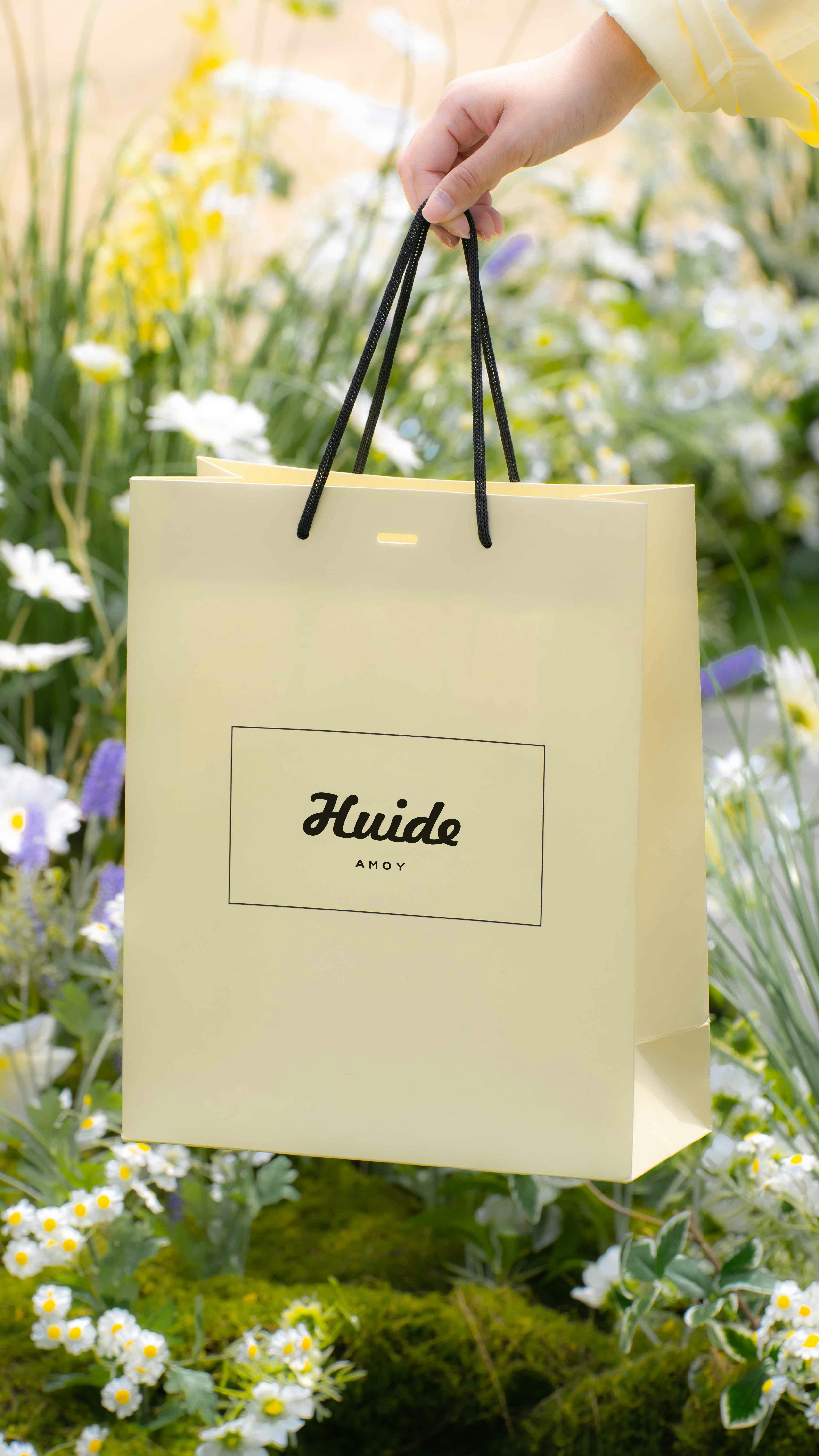Eco-friendly kraft paper bag held by a person amidst a vibrant garden setting.