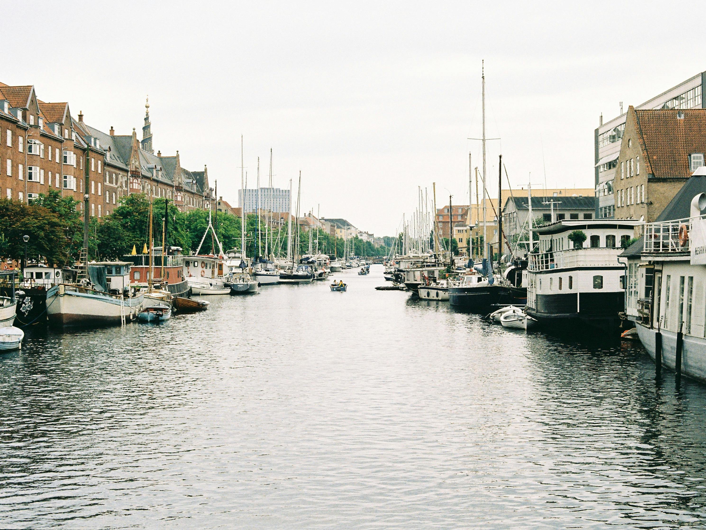 A serene view of Copenhagen's canals lined with houseboats and historic buildings.