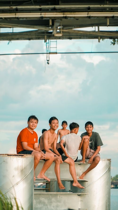 Free A group of teenage boys enjoying a sunny day near a water body in Pontianak, Indonesia. Stock Photo