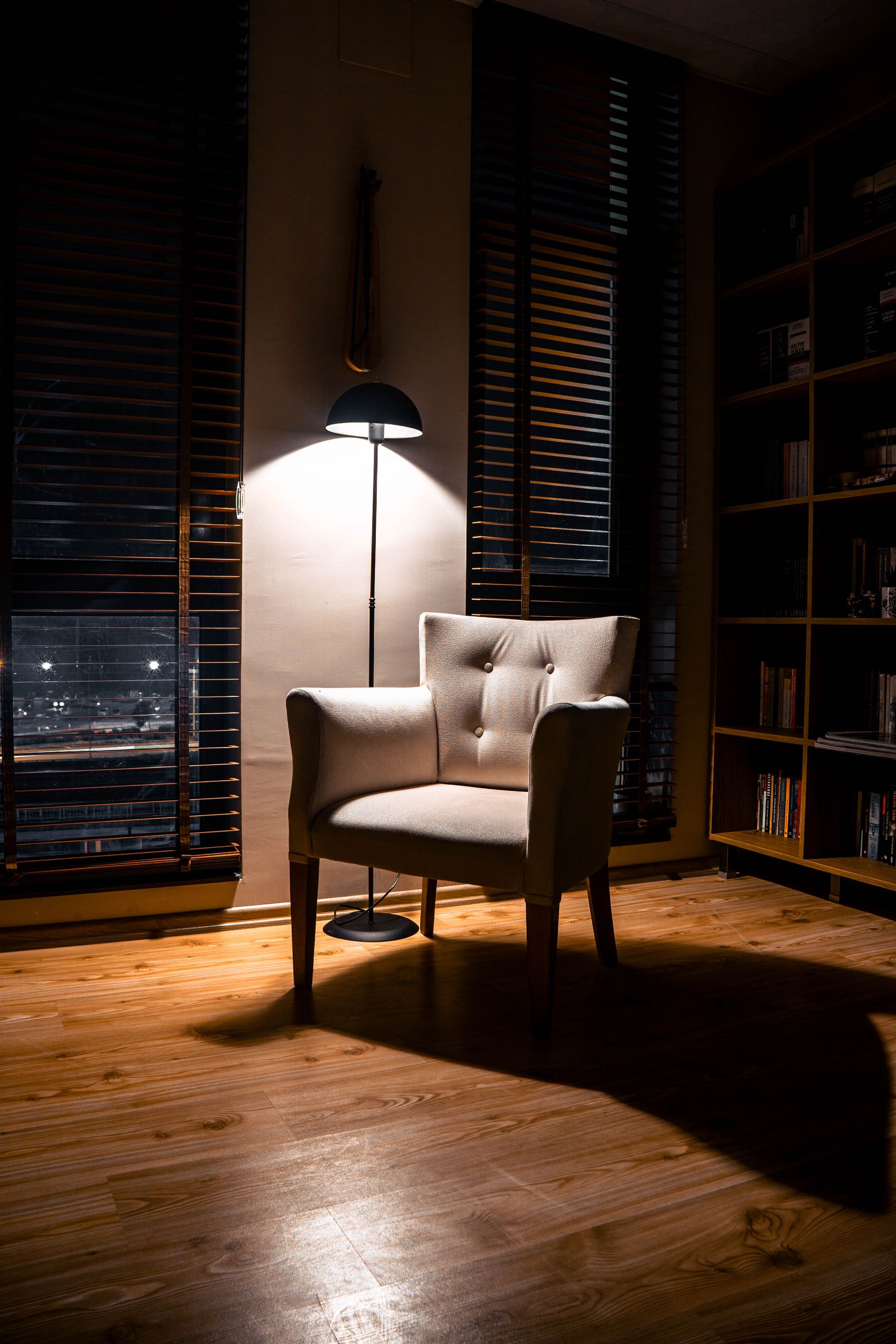 Upholstered chair illuminated by a freestanding floor lamp in a warm reading corner