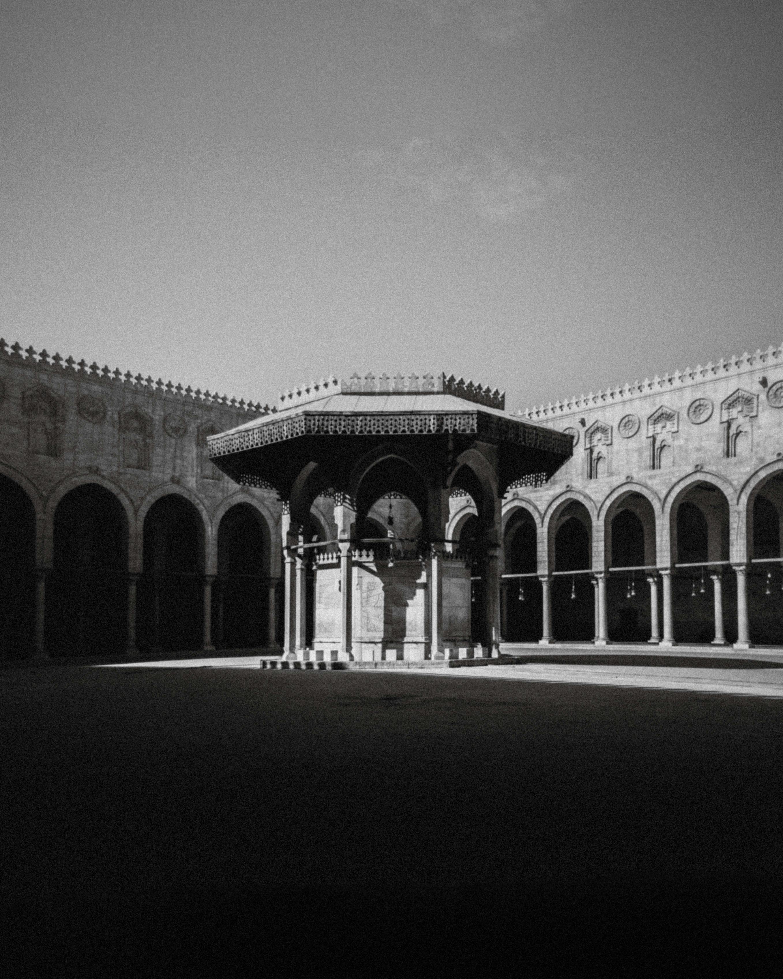 Black and white photo of a historic mosque courtyard in Cairo showcasing Islamic architecture.