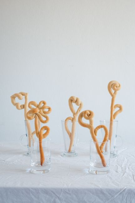 Creative display of twisted breadsticks in glasses on a white tablecloth. Studio setting.