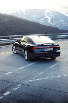 Back view of a black Audi A7 parked on a mountain road in Romania, showcasing its elegance.
