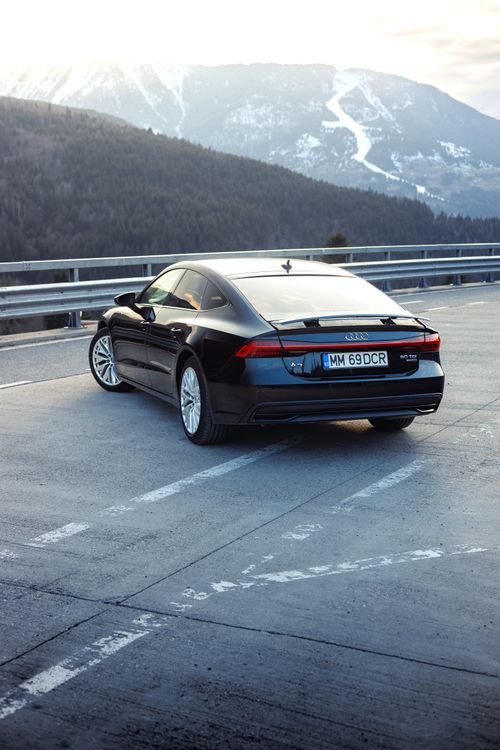 Free Back view of a black Audi A7 parked on a mountain road in Romania, showcasing its elegance. Stock Photo