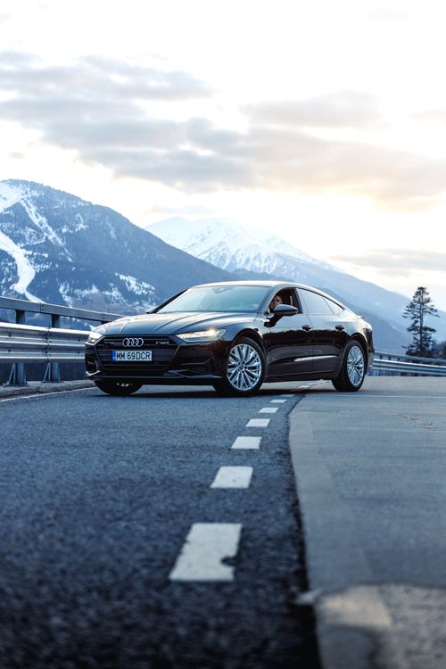Free Sleek black car parked on a scenic mountain road in Romania, offering luxury and elegance. Stock Photo