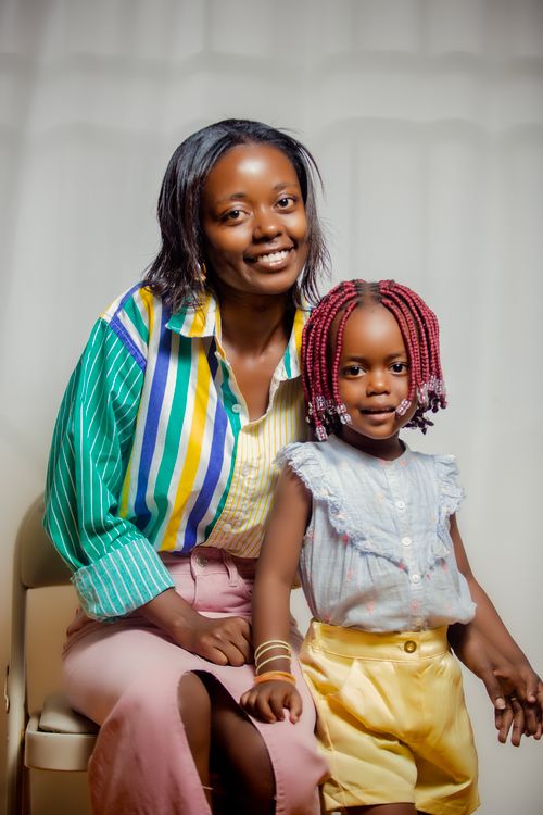 Free Charming portrait of a mother and daughter sitting together, showcasing colorful fashion in a bright setting. Stock Photo