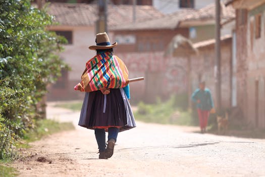 A woman in traditional attire walks down a village street in Chinchero, Peru.