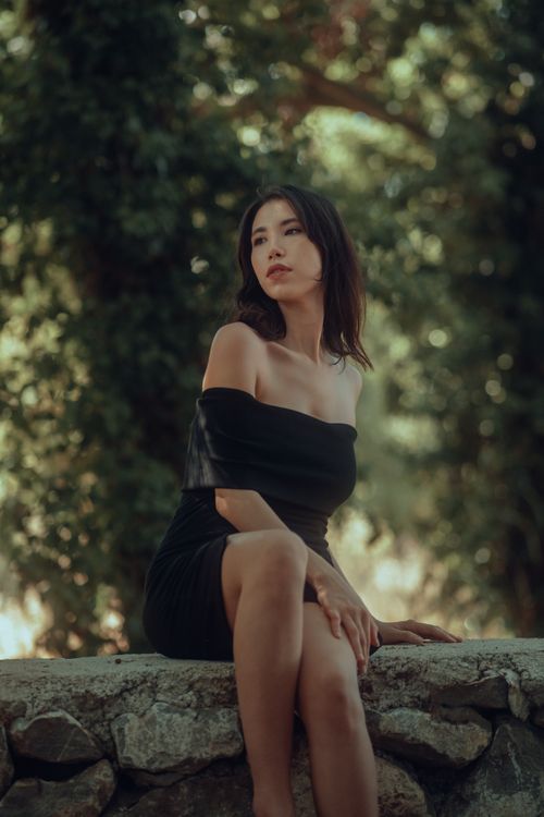 Free Stylish woman in a black dress poses outdoors on a sunny day. Stock Photo